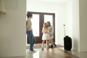 Little kid girl embracing dad leaving family moving out with travel case, sad daughter hugging father in house hall saying goodbye to daddy going away, unhappy child of divorced parents concept