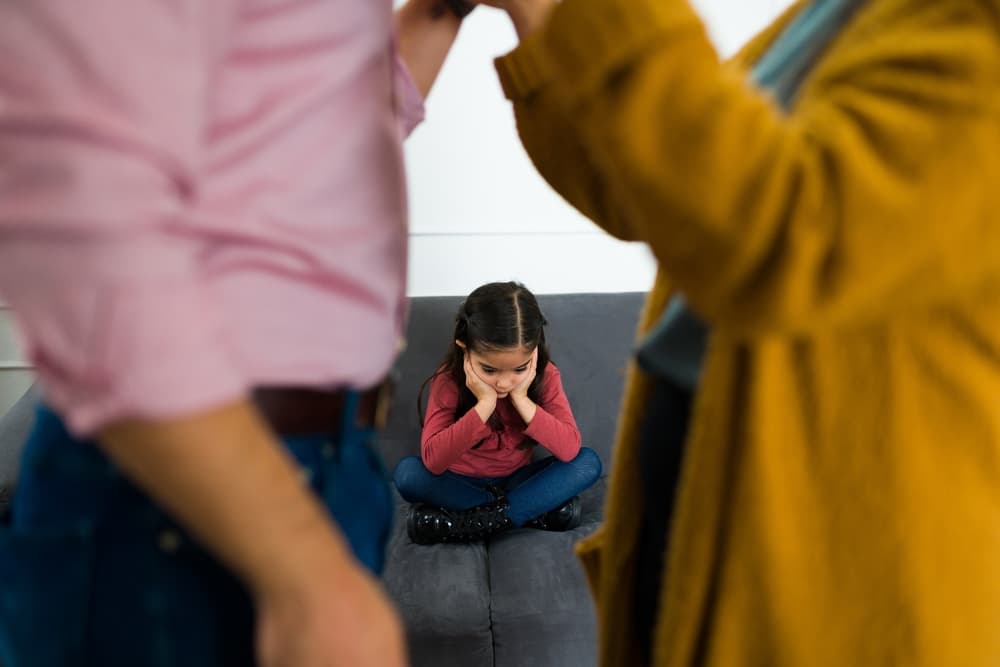 Depressed sad child feeling in the middle of her parents fight about child custody after divorce