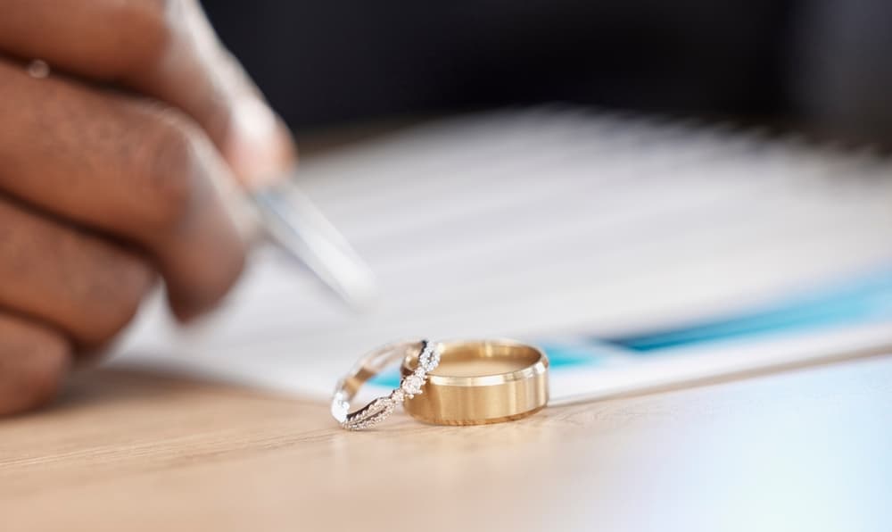 Divorce, rings and signature on paperwork for a lawyer, register wedding or writing on a contract.