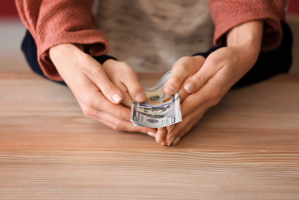 Woman with his son holding dollar banknotes on wooden table. Concept of child support