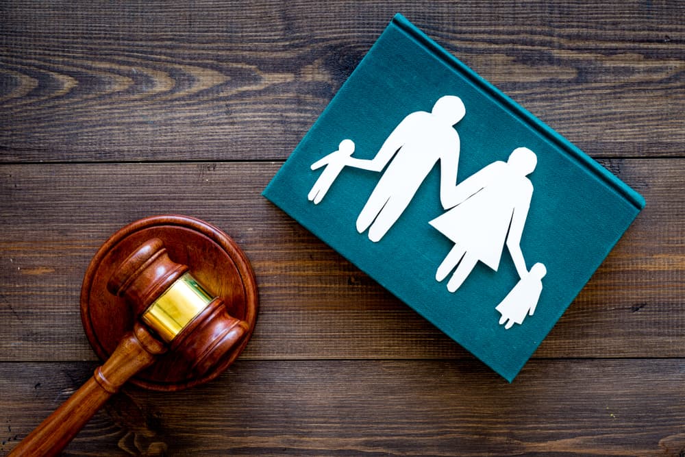 Family law and child custody concept. A paper cutout of a family with children placed near a judge's gavel on a dark wooden background, symbolizing legal rights and family court matters.