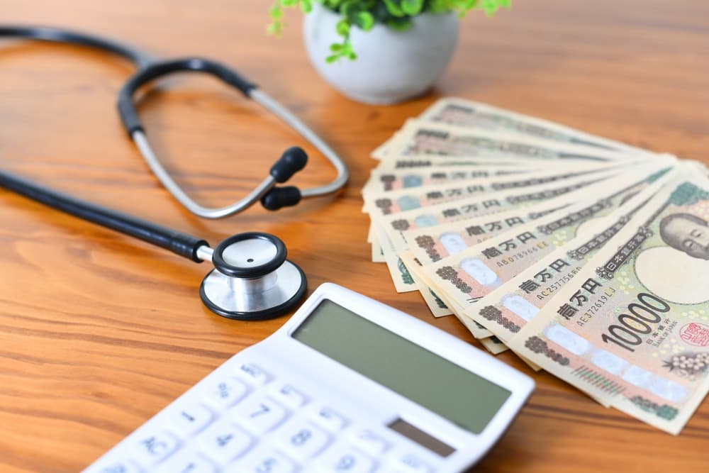 An image featuring medical expenses represented by a stethoscope, a calculator, and banknotes on a desk, symbolizing healthcare costs and financial planning.